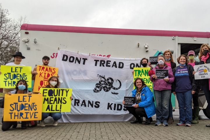 a group of parents and community advocates standing in front of Studio Two Three truck with a banner in the center that reads "Don't Tread on Trans Kids". Community members held pro-trans rights signs like "Let students thrive" and "Trans kids are our kid
